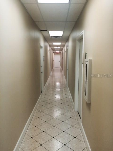 A long, narrow office hallway features beige walls, recessed ceiling lights, and diamond-patterned tile flooring — 2109 E PALM AVENUE, TAMPA, FL