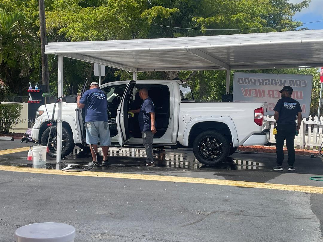 Three men are washing a white pickup truck under a covered outdoor structure — 5390 W 12 Ave, Hialeah FL 33012, HIALEAH, FL