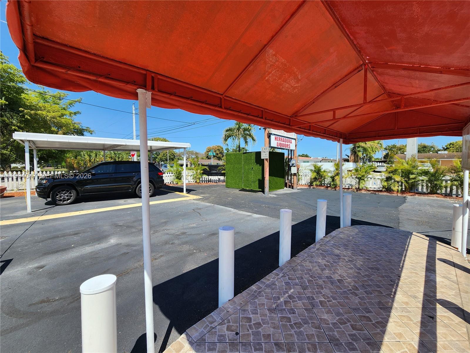 An outdoor parking area features a covered walkway, a red awning, and a liquor store sign — 5390 W 12 Ave, Hialeah FL 33012, HIALEAH, FL