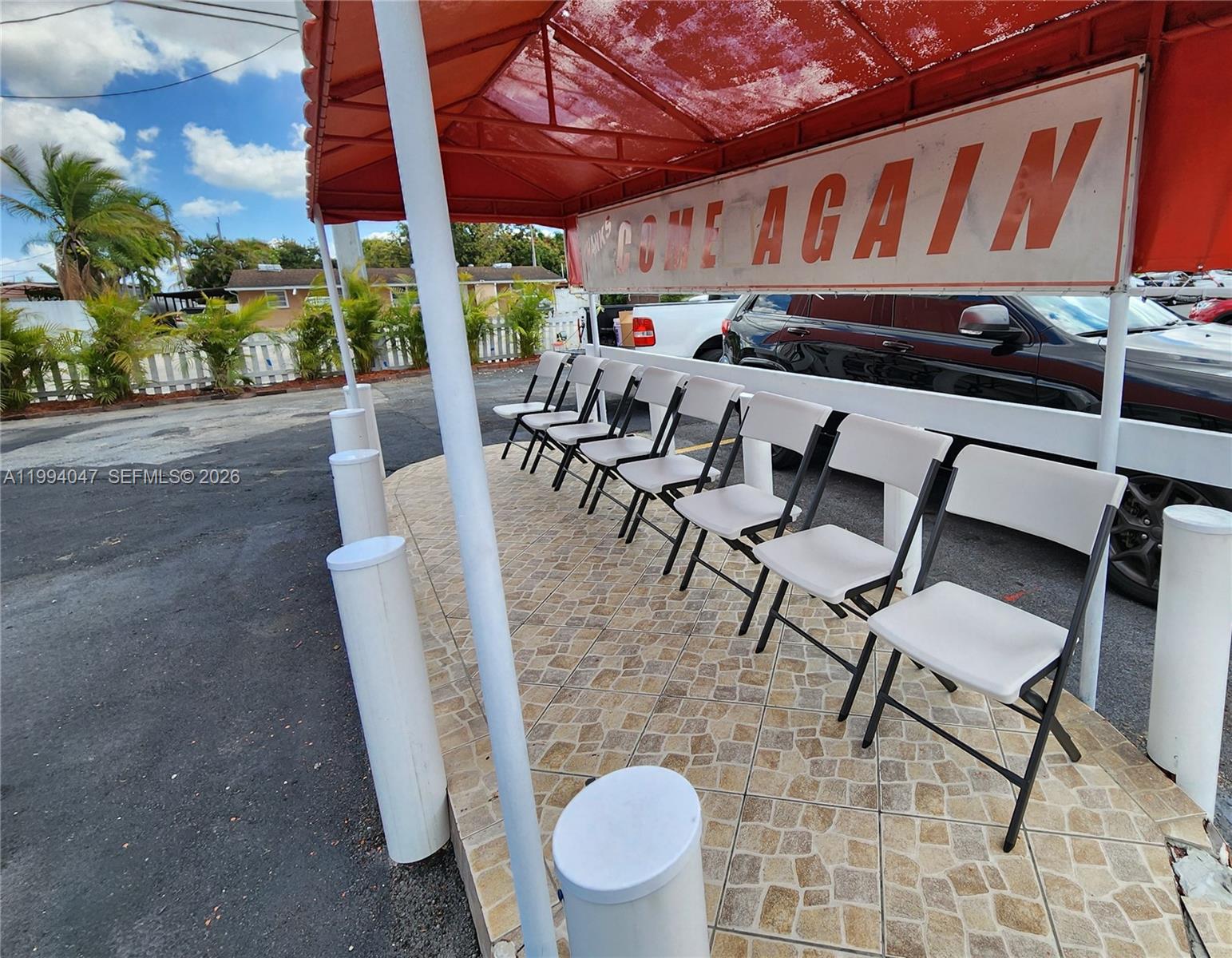 A row of white folding chairs sits under a red awning on a tiled patio — 5390 W 12 Ave, Hialeah FL 33012, HIALEAH, FL