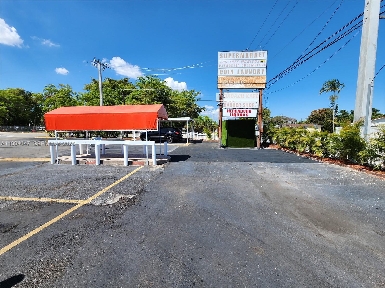An outdoor parking lot features a red canopy, a tall business sign, and palm trees — 5390 W 12 Ave, Hialeah FL 33012, HIALEAH, FL