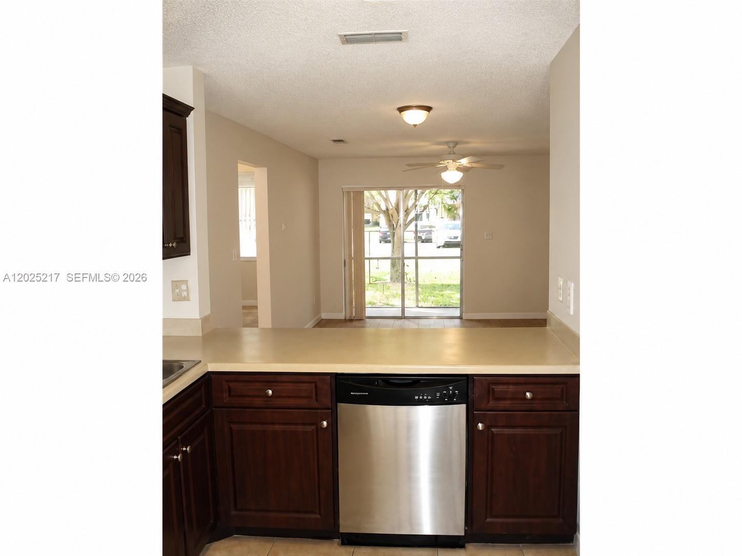 A kitchen with dark wood cabinets and stainless steel appliances overlooks a living area — 2240 SW 81st Ave # 2240, Miramar FL 33025, MIRAMAR, FL