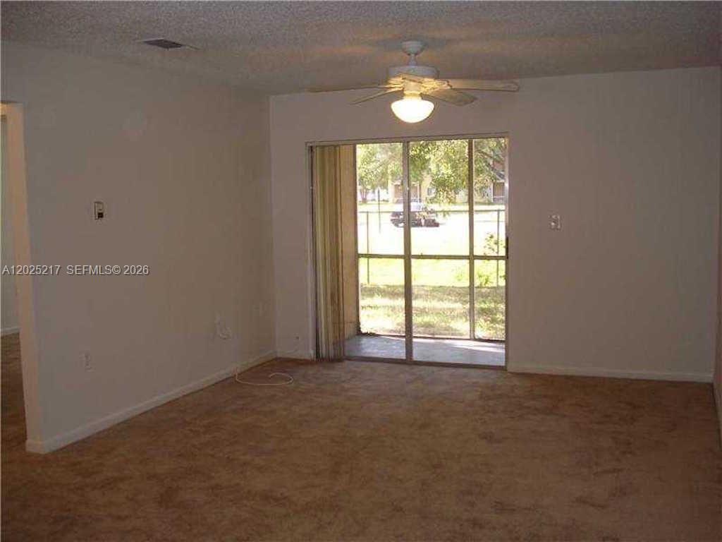 An empty room features beige carpeting, white walls, a ceiling fan, and a sliding glass door — 2240 SW 81st Ave # 2240, Miramar FL 33025, MIRAMAR, FL