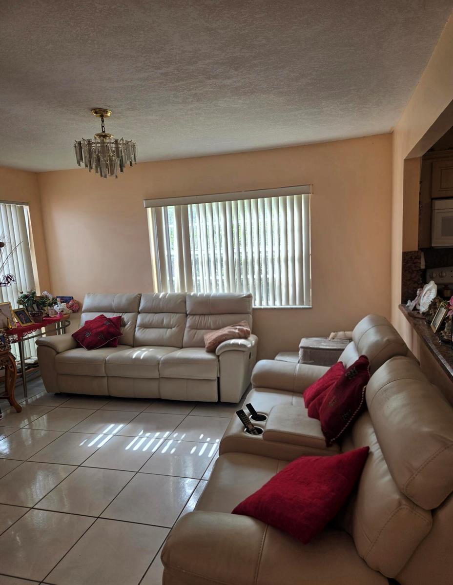 A living room features light-colored tile flooring, two beige leather sofas, and vertical window blinds — 11302 SW 7th Street, Miami FL 33174, MIAMI, FL