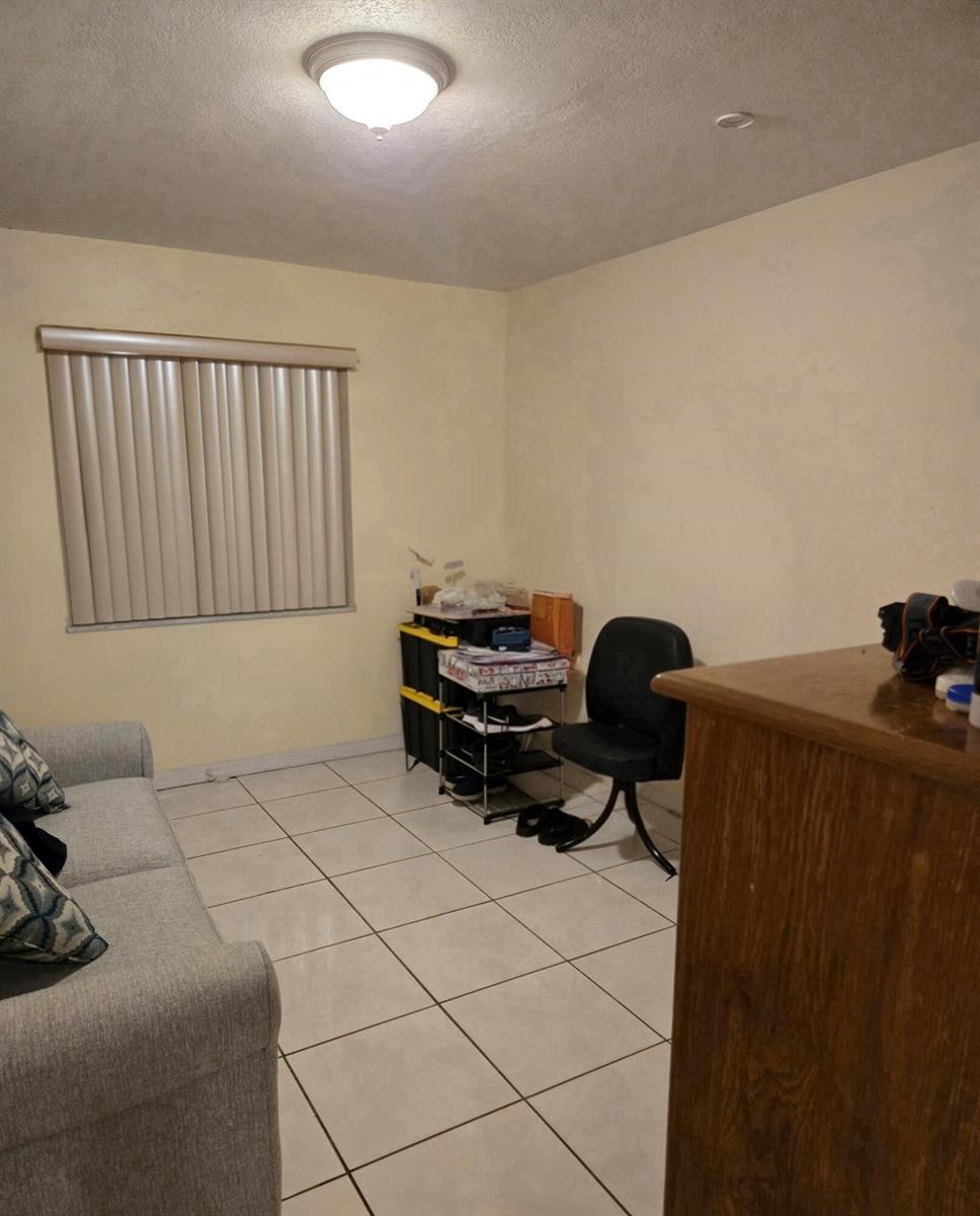 A room with light-colored walls, tile flooring, a window with blinds, and a small desk — 11302 SW 7th Street, Miami FL 33174, MIAMI, FL