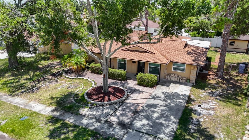 An aerial view of a single-story house with a brown shingled roof and driveway — 7916 WOODGROVE CIRCLE, TAMPA, FL