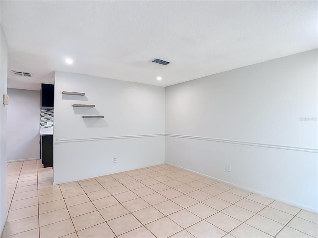 A dining area features light-colored tile flooring, white walls with chair rail molding, and shelves — 7916 WOODGROVE CIRCLE, TAMPA, FL