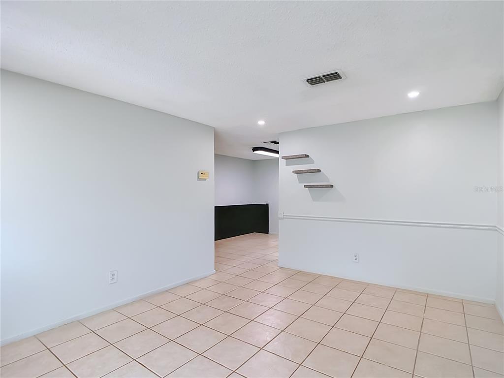 An interior room with light-colored tile flooring, white walls, and three small floating shelves — 7916 WOODGROVE CIRCLE, TAMPA, FL