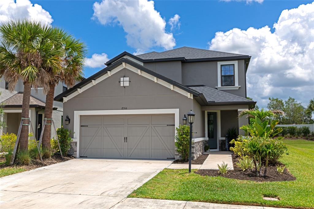 A two-story gray house with a two-car garage and a palm tree in the front — 8366 VELDA TRAIL, SARASOTA, FL