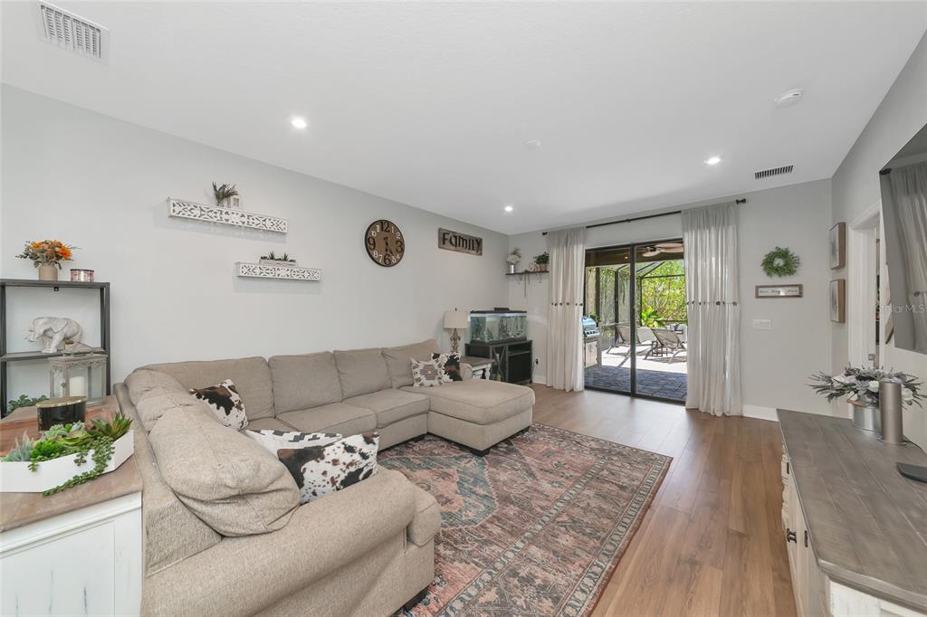 A living room features a sectional sofa, an area rug, and sliding doors to a patio — 8366 VELDA TRAIL, SARASOTA, FL