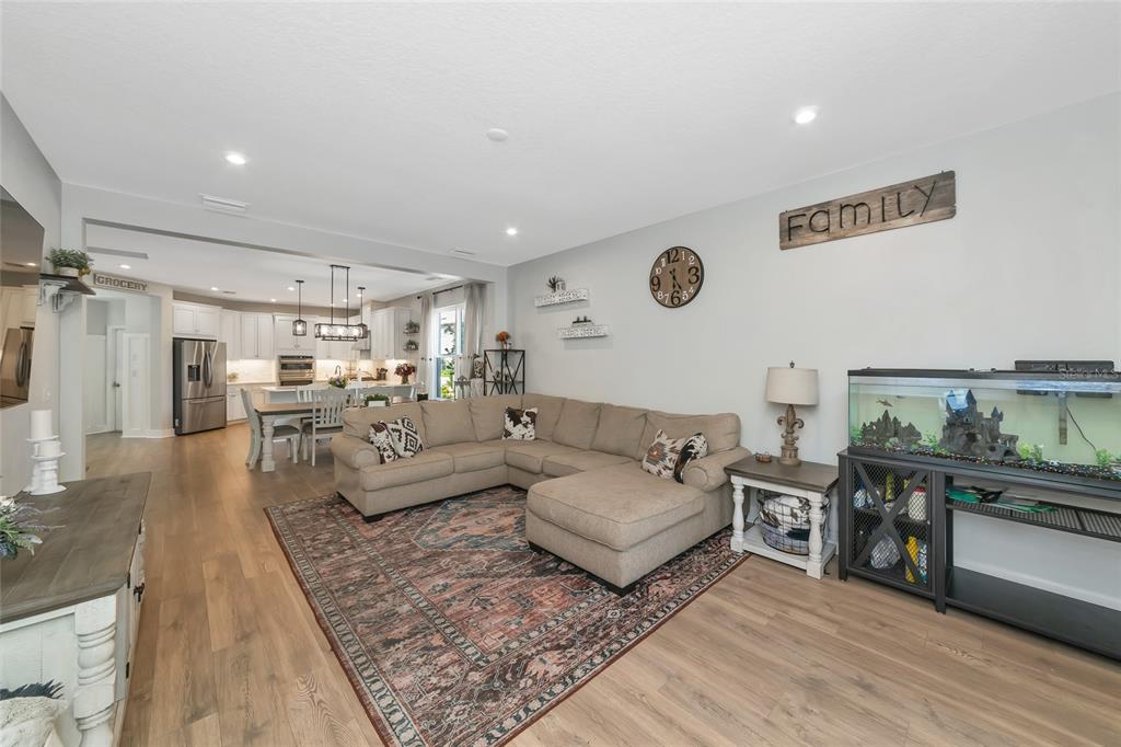 A living room with a sectional sofa, area rug, and fish tank opens to a kitchen — 8366 VELDA TRAIL, SARASOTA, FL