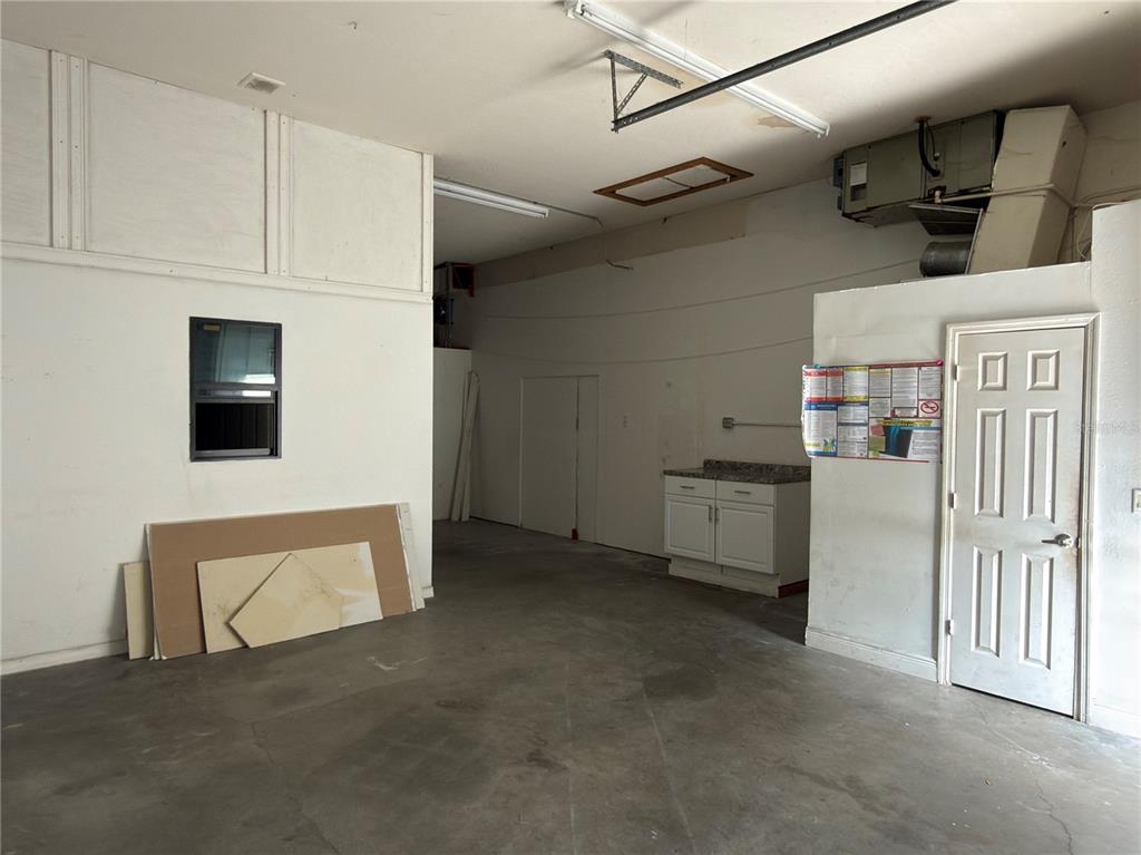 An unfinished garage space features a concrete floor, a small cabinet, and a white door — 18290 PAULSON DRIVE UNIT 4, PORT CHARLOTTE, FL