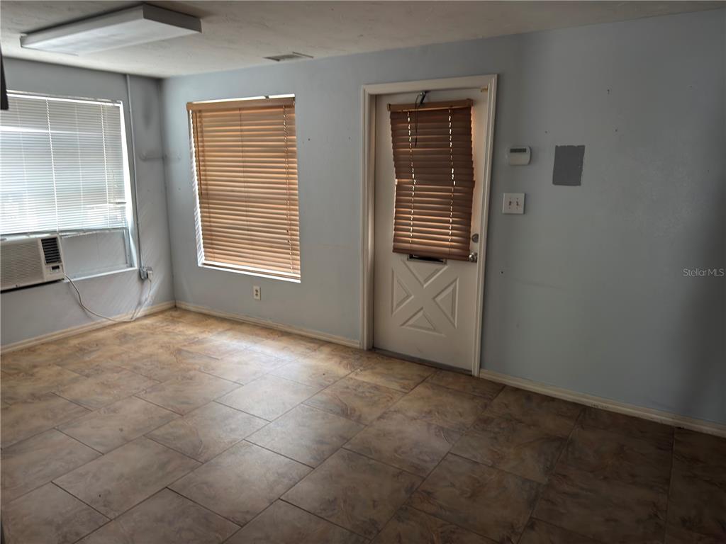 A room with light blue walls, tile flooring, two windows with blinds, and a door — 18290 PAULSON DRIVE UNIT 4, PORT CHARLOTTE, FL