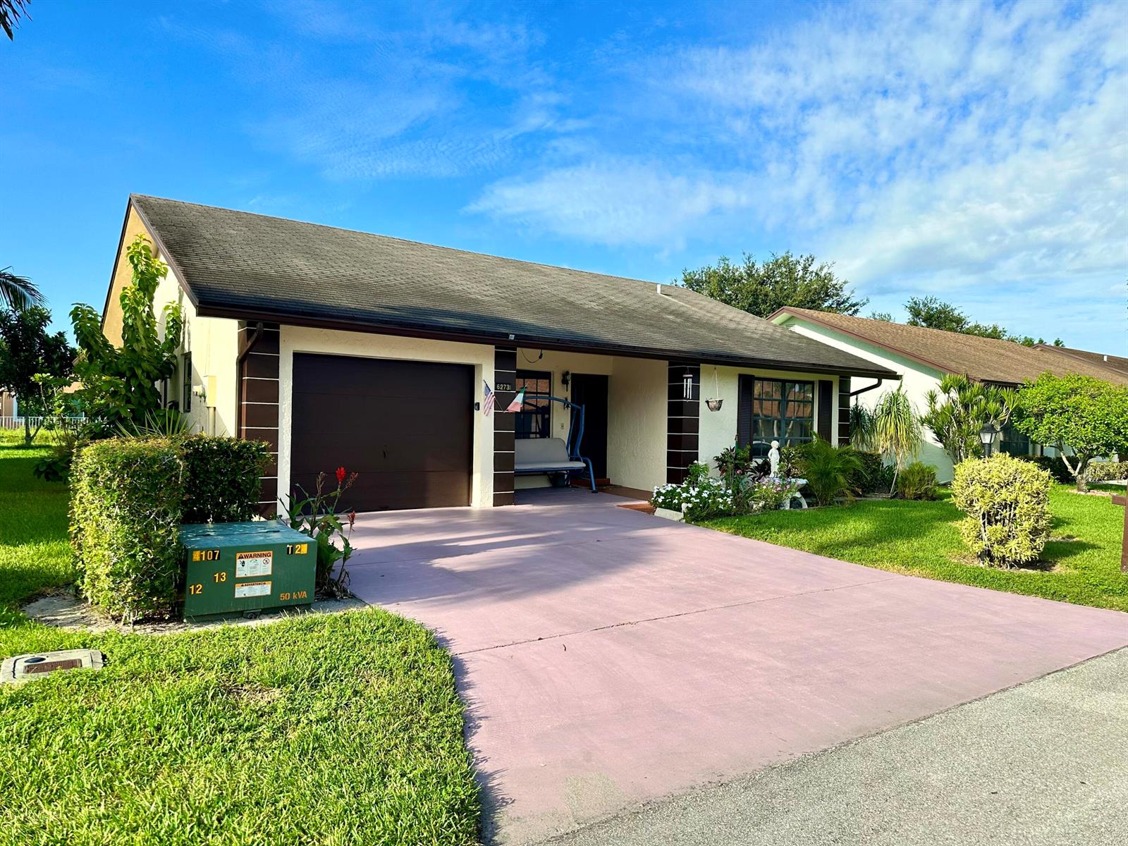 A single-story house with a brown garage door, a driveway, and a green utility box — 6273 Tall Cypress Circle, FL 33463, FL