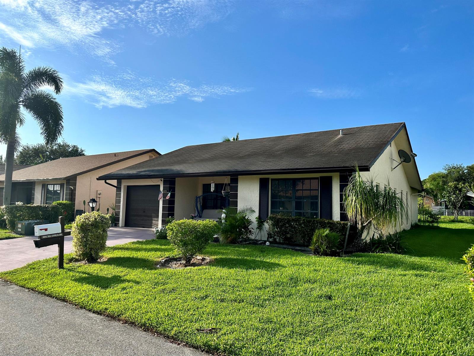 A single-story house with a garage, lawn, and palm tree under a blue sky — 6273 Tall Cypress Circle, FL 33463, FL