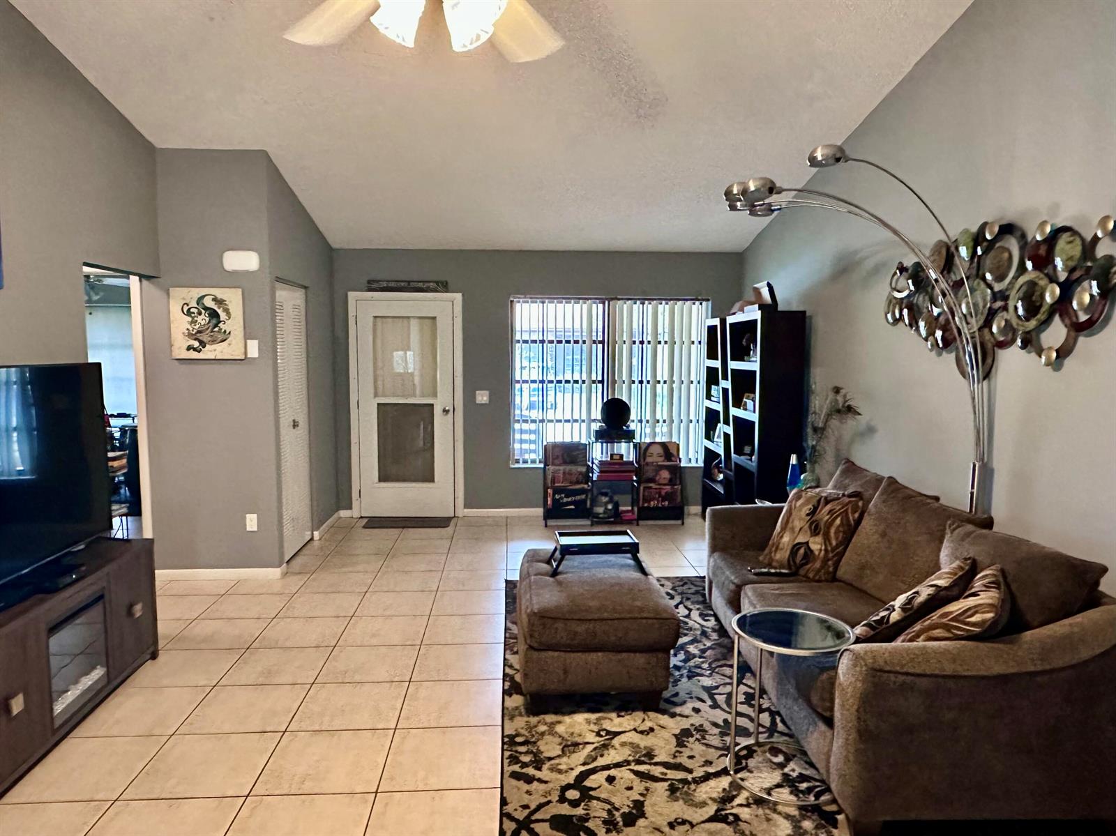 A living room features tile floors, a brown sofa, a television, and a floor lamp — 6273 Tall Cypress Circle, FL 33463, FL