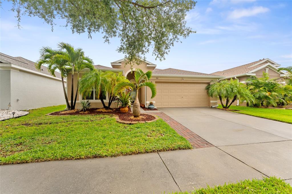 A single-story house with a tan stucco exterior, a two-car garage, and palm trees — 901 PARKER DEN DRIVE, RUSKIN, FL