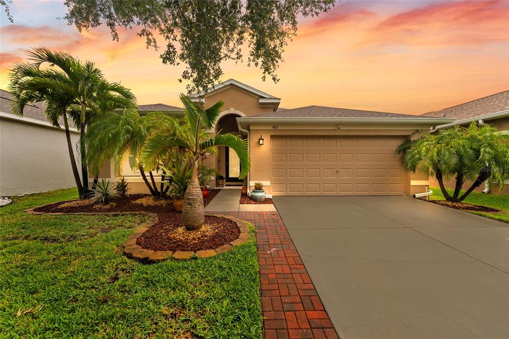 A single-story house with a tan stucco exterior, a two-car garage, and a landscaped front yard — 901 PARKER DEN DRIVE, RUSKIN, FL