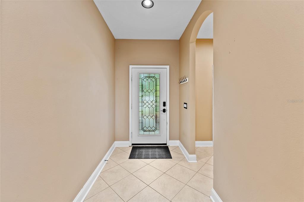 An entryway features beige walls, a tiled floor, and a white door with glass panels — 901 PARKER DEN DRIVE, RUSKIN, FL