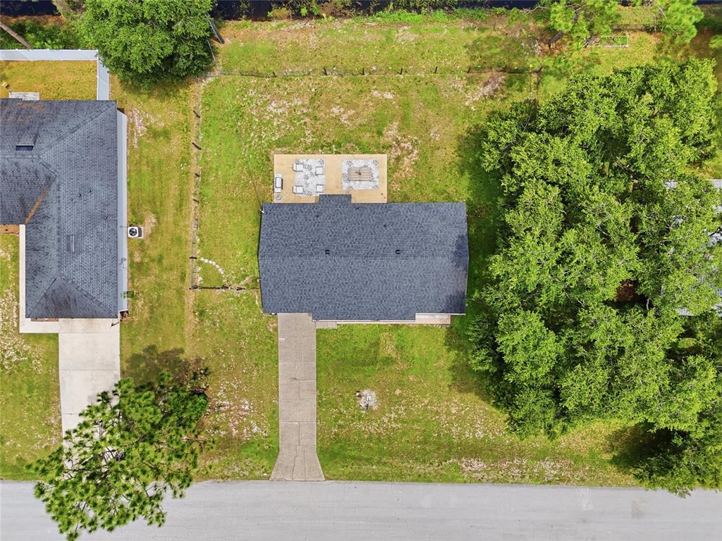 An aerial view shows a house with a driveway, a backyard patio, and large trees — 3672 RONDA DRIVE, DELTONA, FL