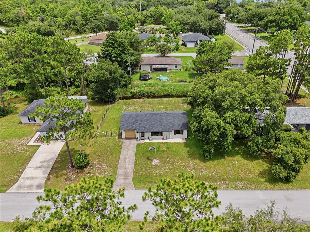 An aerial view shows a single-story house with a dark roof, driveway, and large yard — 3672 RONDA DRIVE, DELTONA, FL