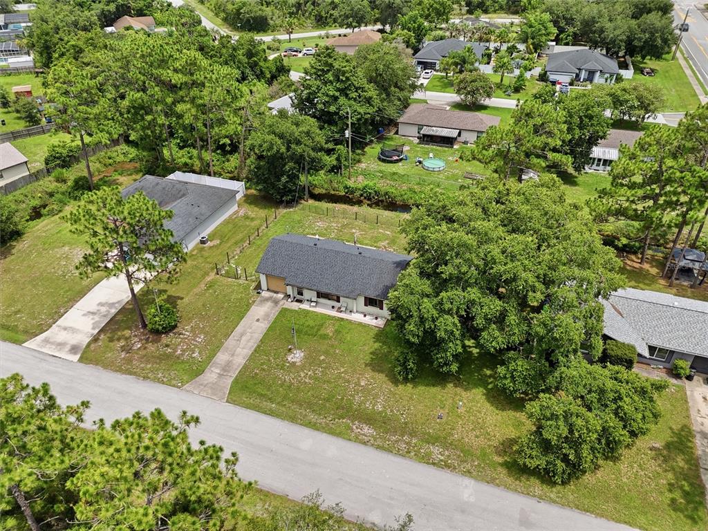 An aerial view shows a single-story house with a driveway and large trees — 3672 RONDA DRIVE, DELTONA, FL