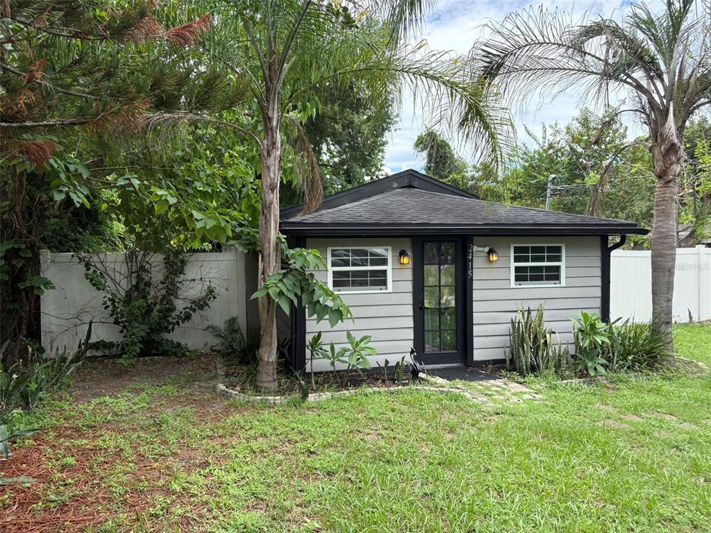 A small, gray-sided detached building with a dark roof, a glass door, and two windows — 2415 MAYER STREET, ORLANDO, FL