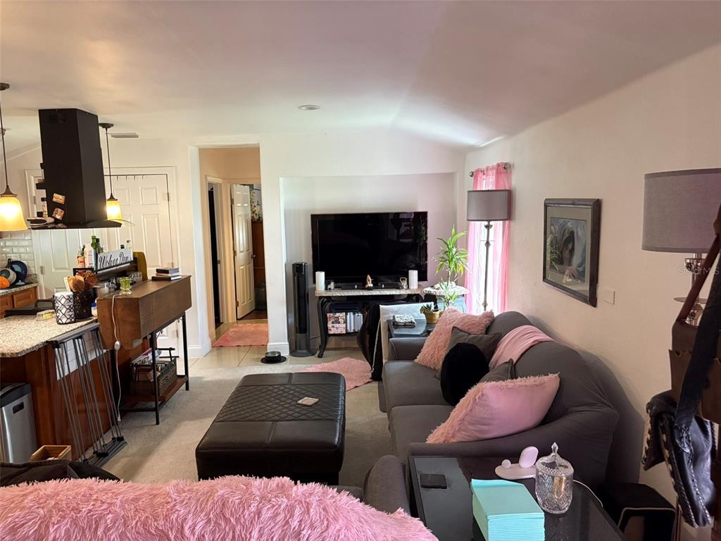 A living room features a gray sofa, a black ottoman, and a television in a nook — 2415 MAYER STREET, ORLANDO, FL