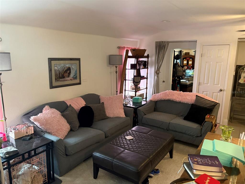A living room features two gray sofas, a dark leather ottoman, and pink accent pillows — 2415 MAYER STREET, ORLANDO, FL