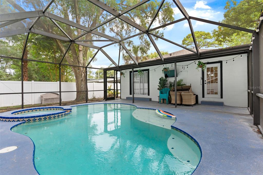 A screened-in patio features a swimming pool with a hot tub and outdoor seating — 1507 E HENRY AVENUE, TAMPA, FL