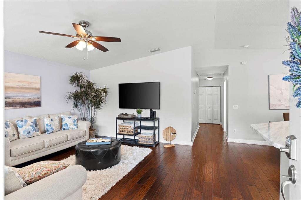 A living room features a beige sofa, a black ottoman, and dark hardwood flooring — 1507 E HENRY AVENUE, TAMPA, FL