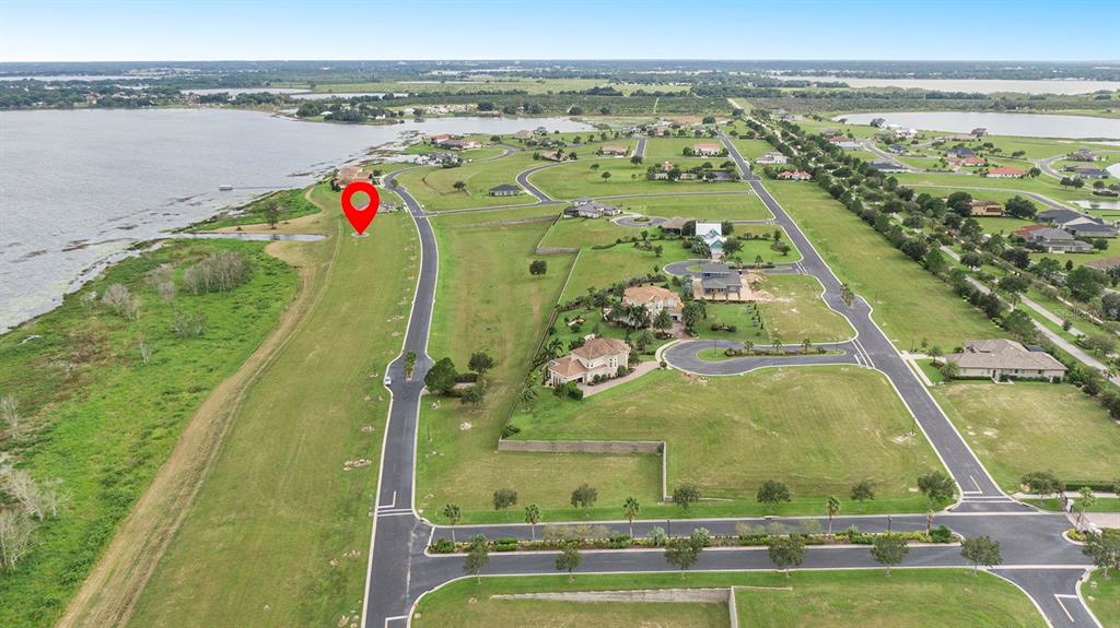 An aerial view shows a vacant waterfront lot marked with a red pin in a neighborhood — 288 CALADIUM AVENUE, LAKE ALFRED, FL