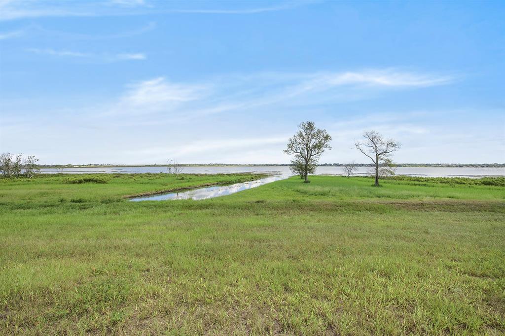 A grassy field leads to a narrow waterway and a large body of water — 288 CALADIUM AVENUE, LAKE ALFRED, FL