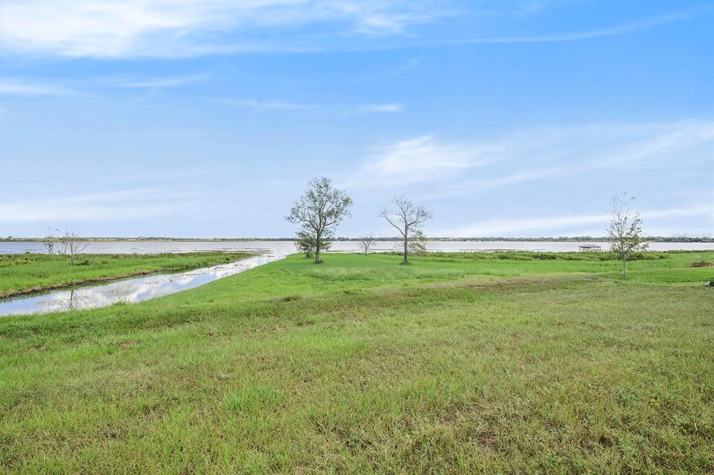 A grassy field leads to a narrow canal and a large lake under a blue sky — 288 CALADIUM AVENUE, LAKE ALFRED, FL