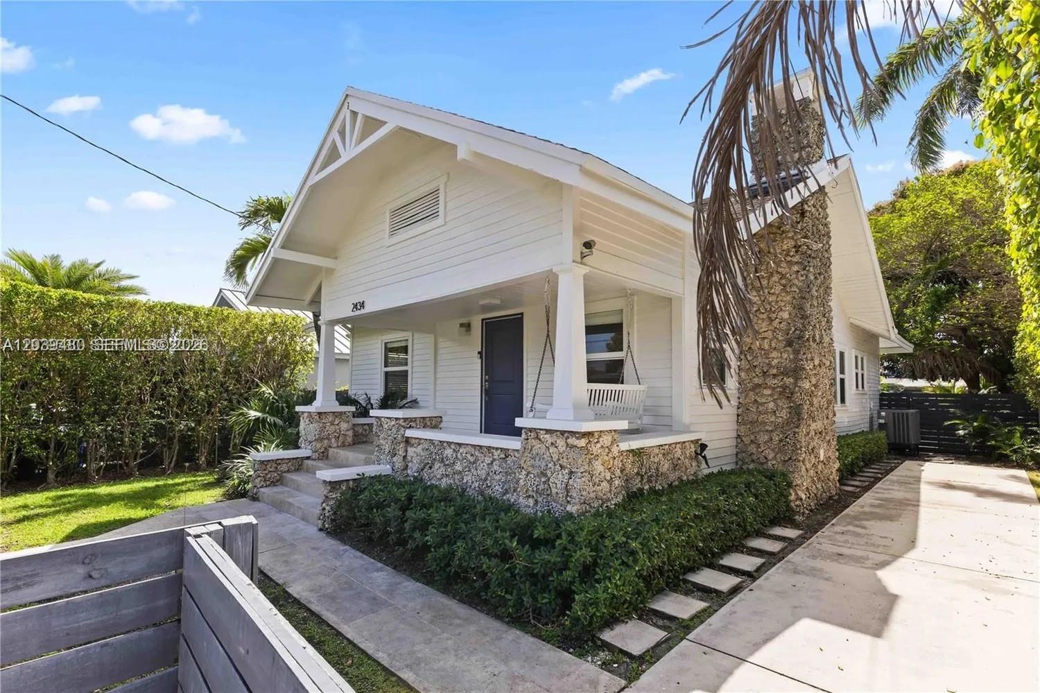 A white bungalow features a stone chimney, a front porch with a swing, and landscaping — 2434 SW 15th St # 2434, Miami FL 33145, MIAMI, FL