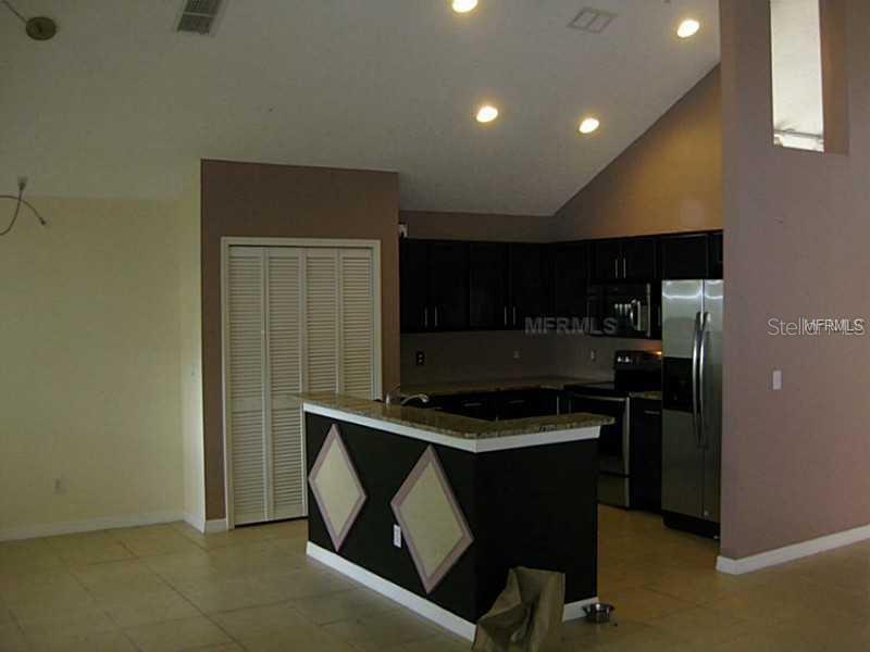 A kitchen with dark cabinets, stainless steel appliances, and a breakfast bar with diamond accents — 4032 BOLINAS COURT, ORLANDO, FL