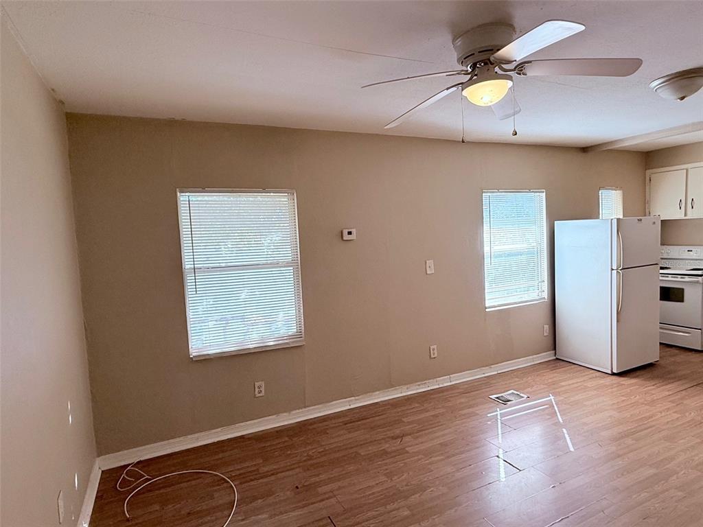 A room with wood-look flooring, two windows, a ceiling fan, and a white refrigerator — 986 22ND AVENUE S UNIT 3, ST PETERSBURG, FL
