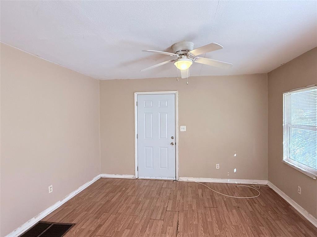 An empty room features tan walls, wood-look flooring, a ceiling fan, and a white door — 986 22ND AVENUE S UNIT 3, ST PETERSBURG, FL