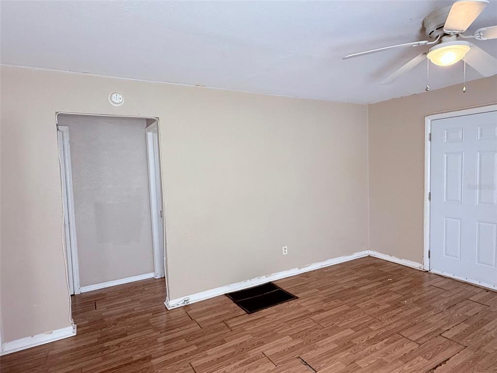 An empty room features wood-look flooring, beige walls, a ceiling fan, and a white door — 986 22ND AVENUE S UNIT 3, ST PETERSBURG, FL