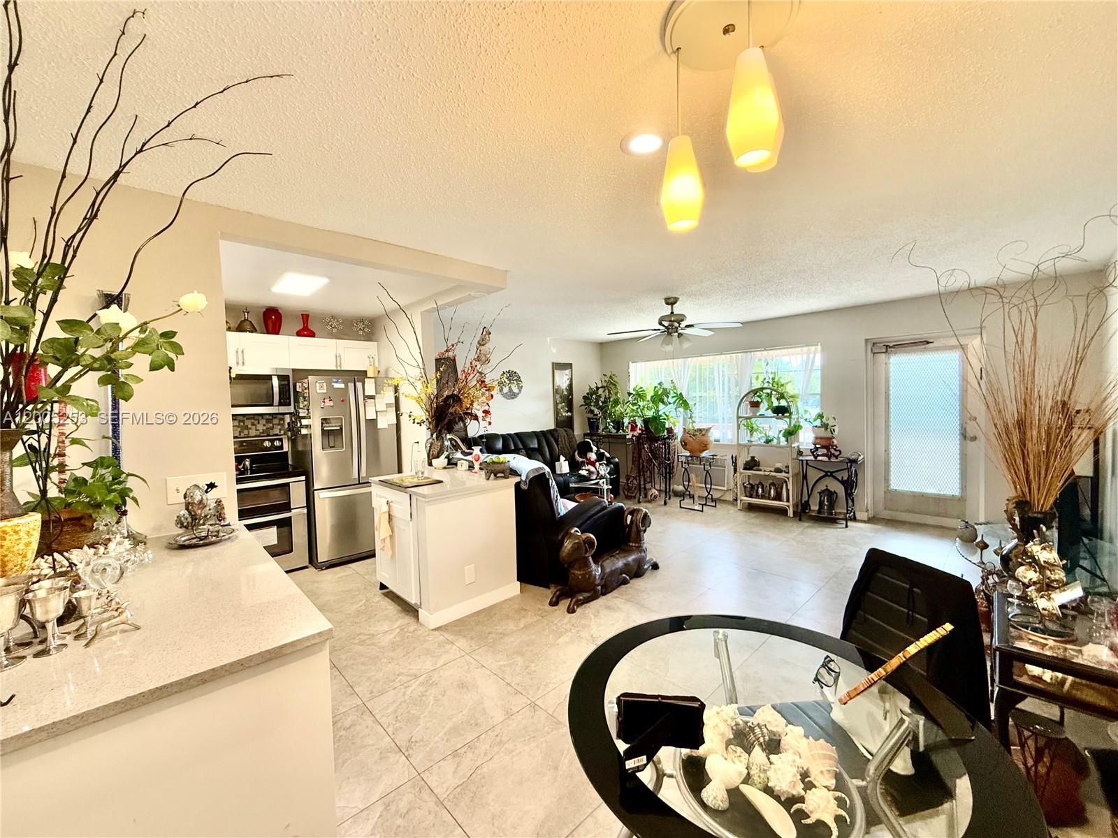 An open-concept kitchen and living area features tile flooring, white cabinetry, and a dining table — 431 Chatham U # U, West Palm Beach FL 33417, WEST PALM BEACH, FL