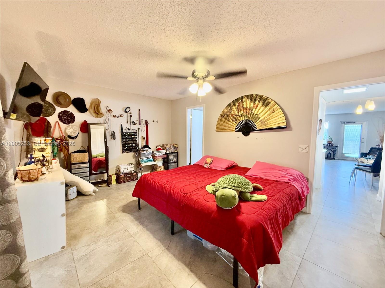 A bedroom features a red bedspread, a large wall fan, and tiled flooring — 431 Chatham U # U, West Palm Beach FL 33417, WEST PALM BEACH, FL
