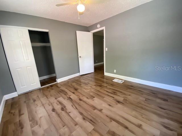 A bedroom features light wood-look flooring, gray walls, a ceiling fan, and two white doors — 2511 10TH AVENUE S, ST PETERSBURG, FL