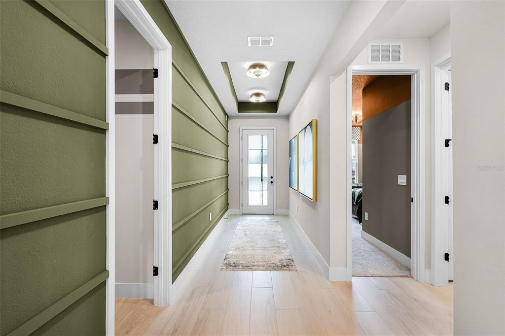 A hallway features light wood flooring, a green horizontal-planked accent wall, and a recessed ceiling — 558 EMERALD GROVE DRIVE, APOPKA, FL
