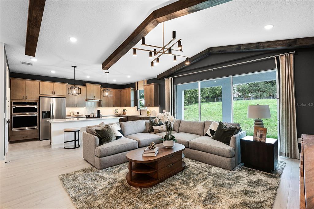 An open-concept living room and kitchen feature vaulted ceilings with exposed wooden beams — 558 EMERALD GROVE DRIVE, APOPKA, FL