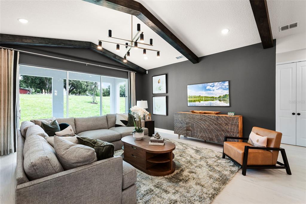 A living room features a gray sectional, a wooden coffee table, and dark ceiling beams — 558 EMERALD GROVE DRIVE, APOPKA, FL
