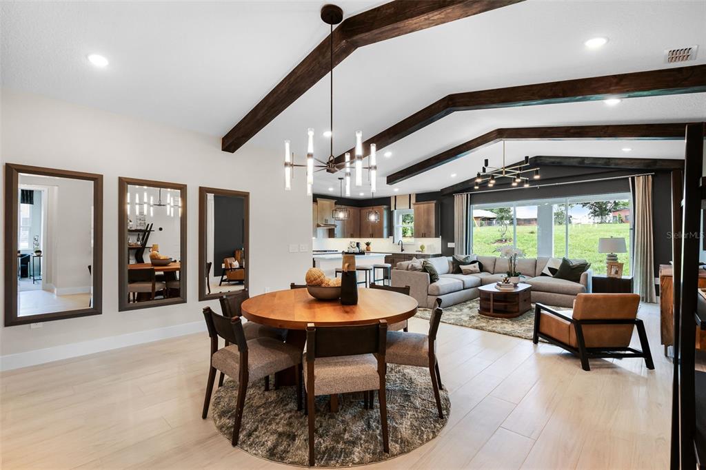 An open-concept living and dining area features vaulted ceilings with exposed wooden beams — 558 EMERALD GROVE DRIVE, APOPKA, FL