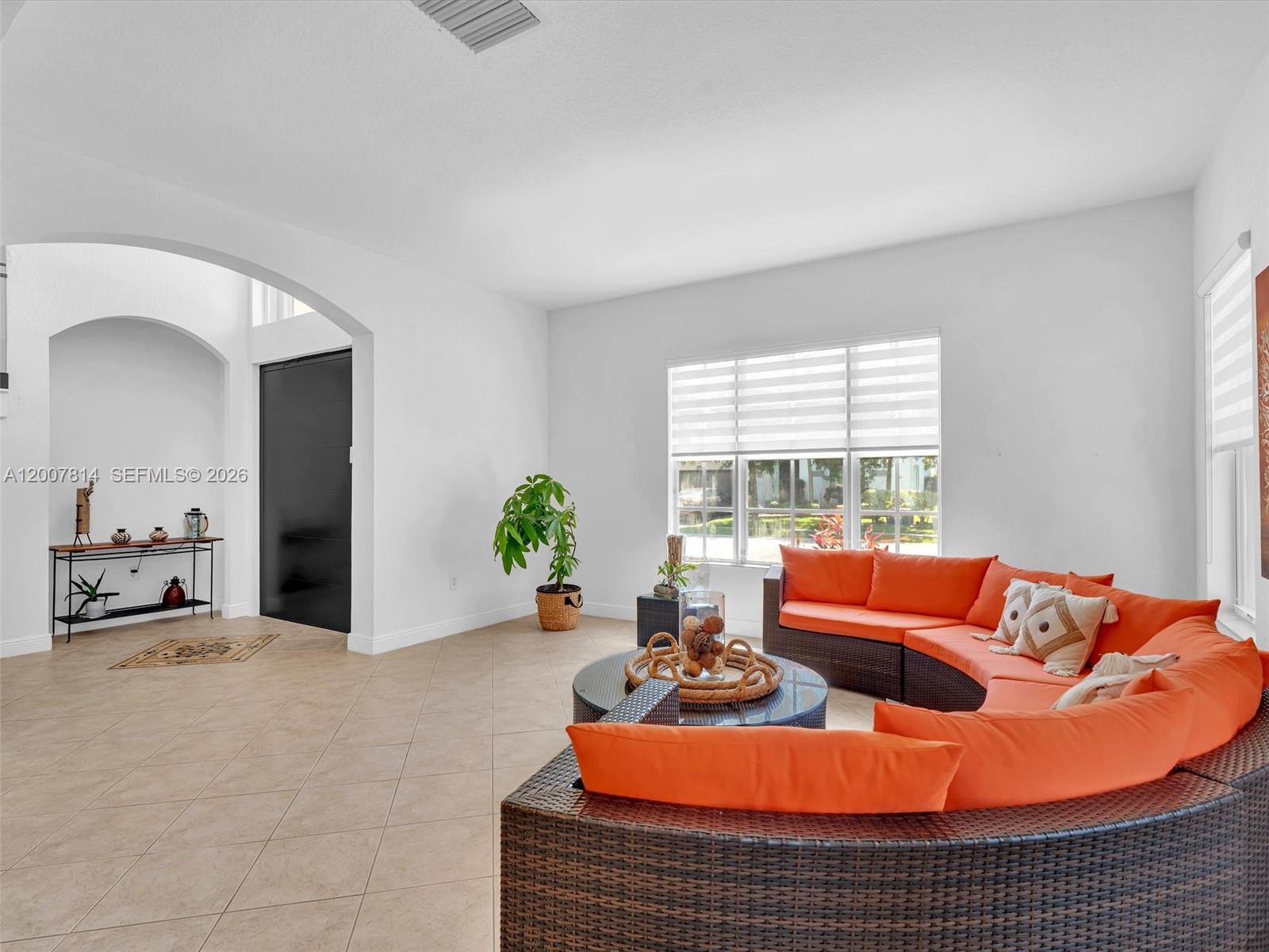 A living room features a curved orange sofa, tile flooring, and a black door — 4961 SW 173rd Ave, Miramar FL 33029, MIRAMAR, FL