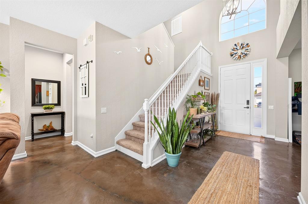 A bright entryway features a staircase, a large potted plant, and polished concrete flooring — 1135 TOLUKE POINT, ORLANDO, FL