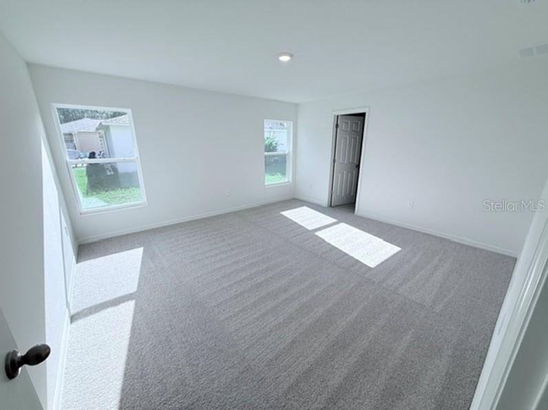 An empty bedroom features white walls, gray carpeting, two windows, and a doorway — 40 LAGUNA FOREST TRAIL, PALM COAST, FL