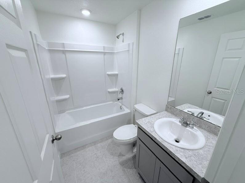 A bathroom features a white tub-shower combination, a gray vanity, and a toilet — 40 LAGUNA FOREST TRAIL, PALM COAST, FL